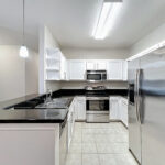Kitchen with stainless steel appliances, white cabinets and black coutnertops.