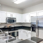 Kitchen with stainless steel appliances, white cabinets and black countertops.