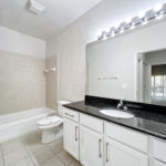 Spacious bathroom with white cabinets and vanity sink, large shower and tub combination.