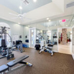 Gym with large windows and cardio and strength equipment.