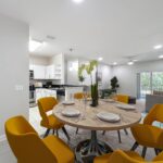 Dining room space with table, bright colored chairs, overhead LED lights, with living room and kitchen nearby in open concept space.