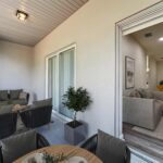 Outdoor covered patio space with two large sliding glass doors, one with access to the living and dining room space.
